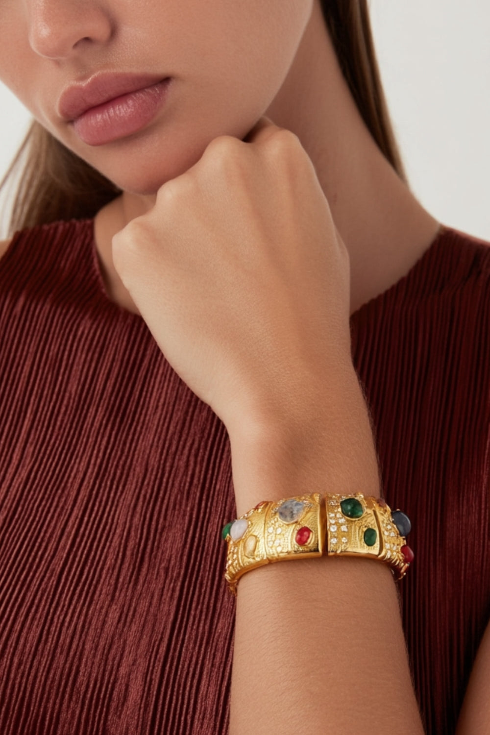 A model wearing a yellow gold bracelet with multicolor colorful gemstones and crystals.