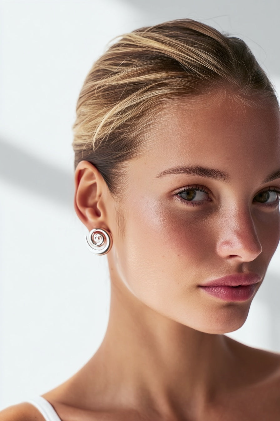 Model wearing the Cleo Earrings – 14k white gold-plated chunky hoop earrings with spiral design.