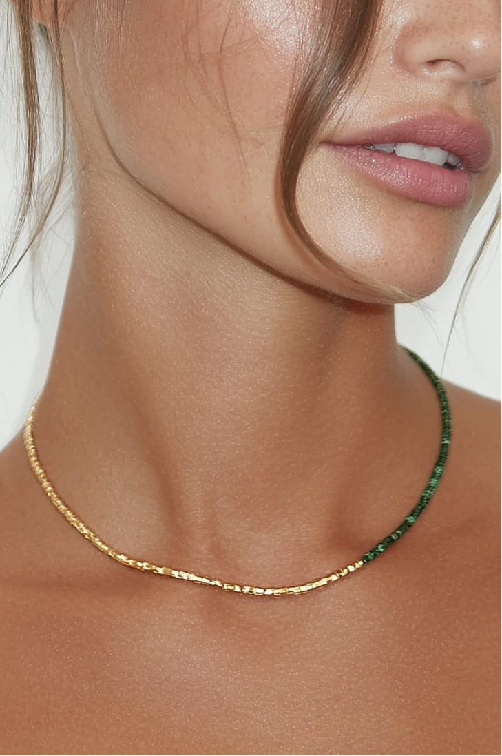 Model wearing the Lucia Necklace Verdé – slim gold-plated necklace with deep green gemstone beads and gold accents