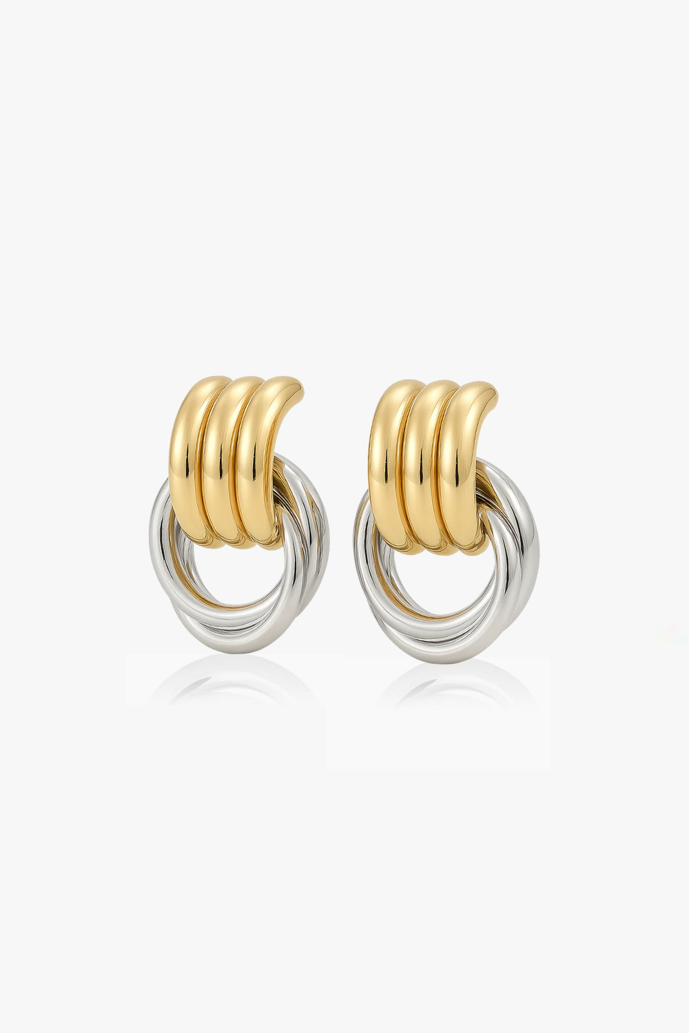 Chunky layered yellow gold and white gold two tone hoop earrings on a white background.