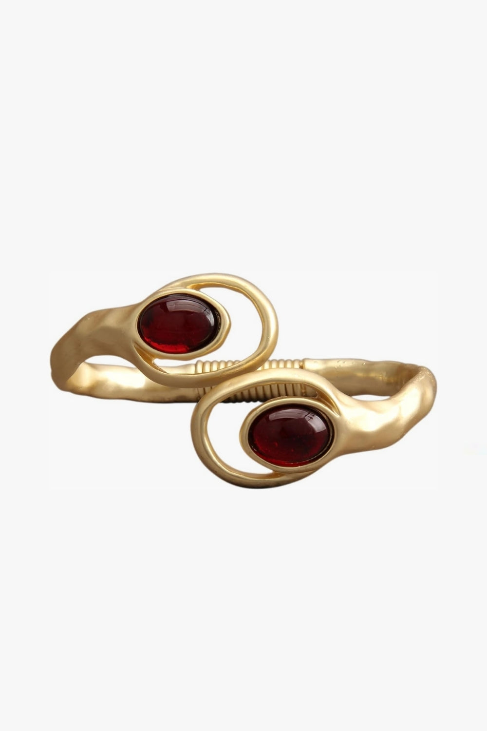 Yellow gold bracelet open cuff with two red gemstones on a white background.