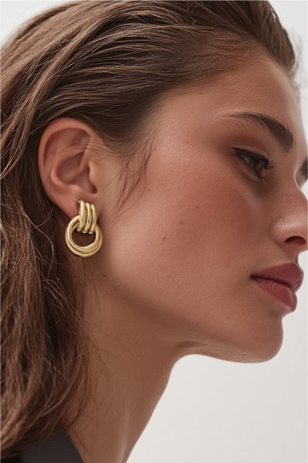 Close-up of a model wearing yellow gold chunky layered hoop earrings studs.