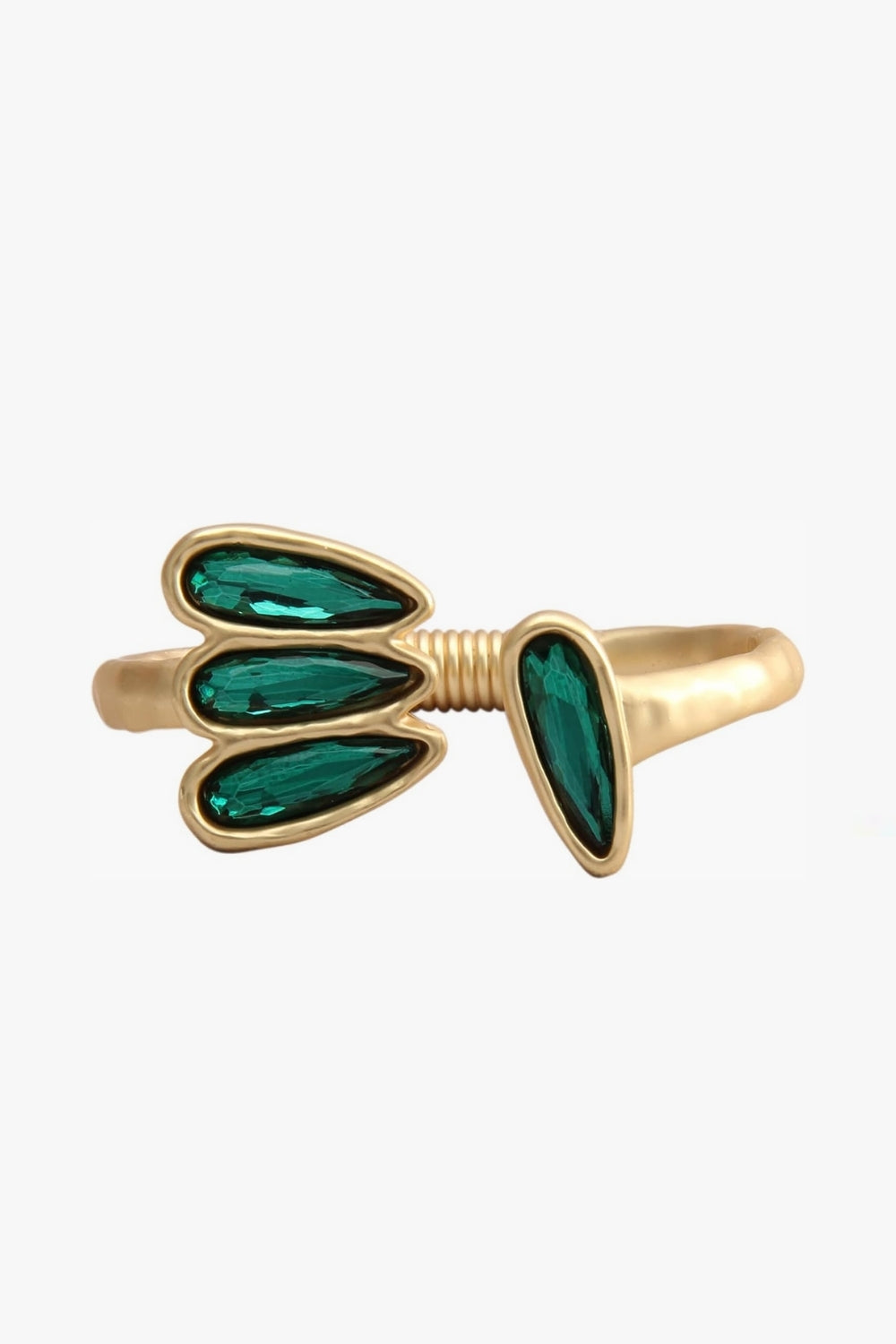 Yellow gold open cuff bracelet with emerald green gemstones on a white background, asymmetrical shape, retro style.