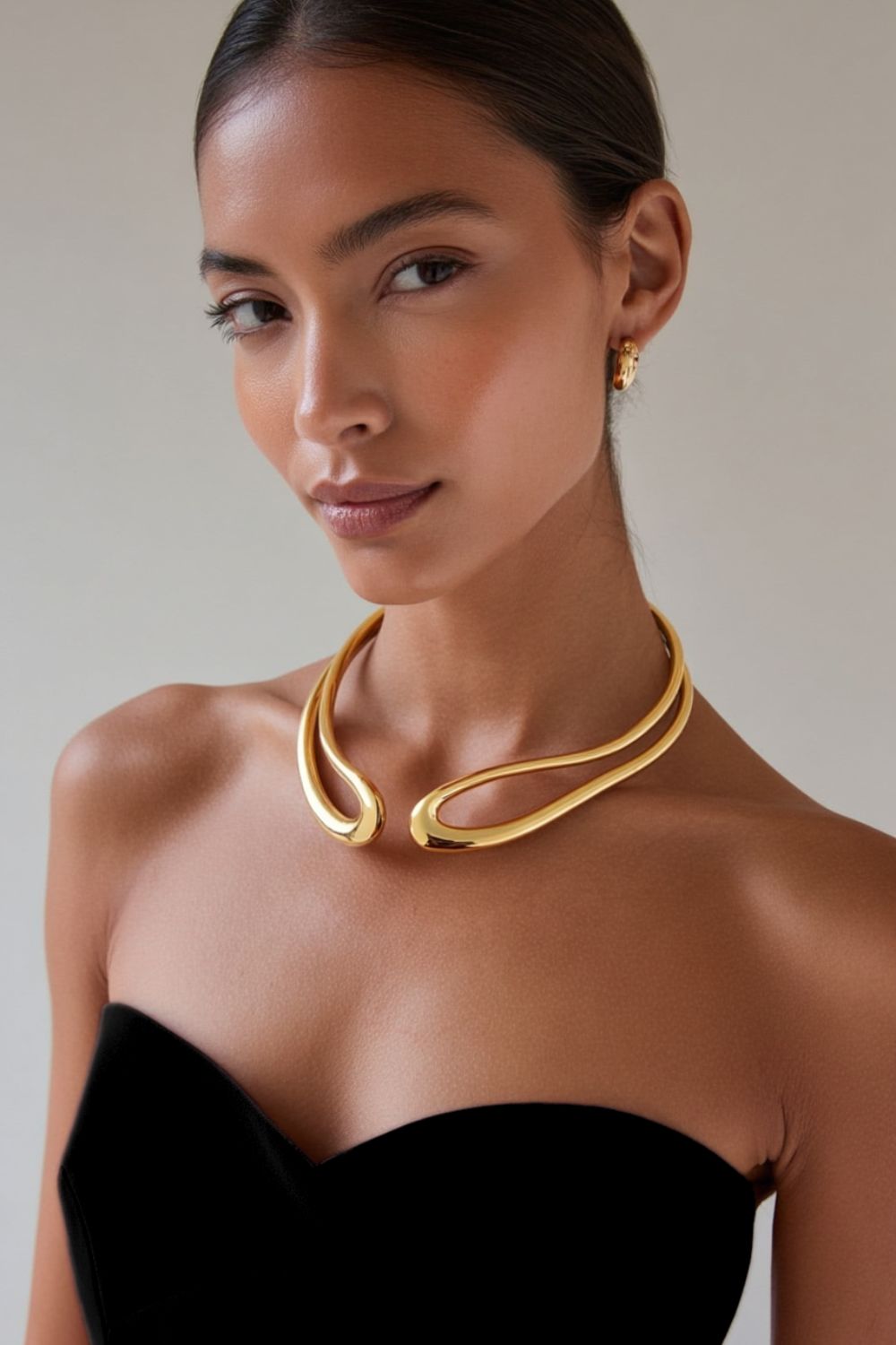 model wearing a yellow gold sculptural neckpiece, abstract, open collar necklace.