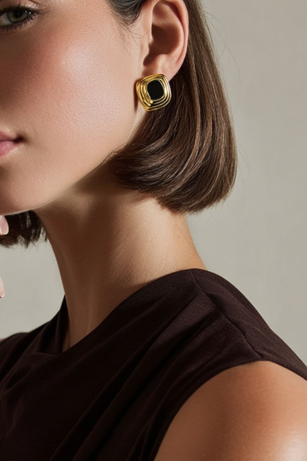 model wearing chunky yellow gold framed earrings with black center, vintage feel.