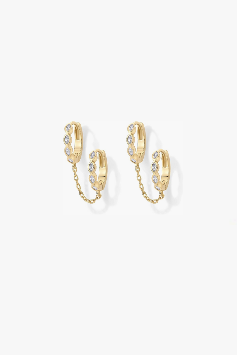 Selena yellow gold marquise huggie earrings linked by chain.