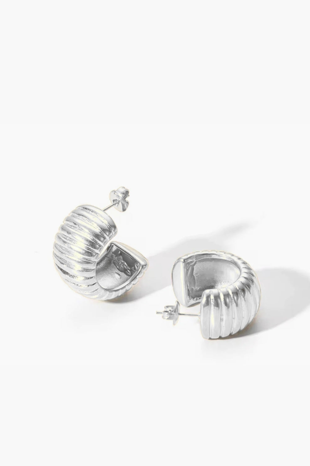 white gold huggie hoop earrings, ribbed on a white background