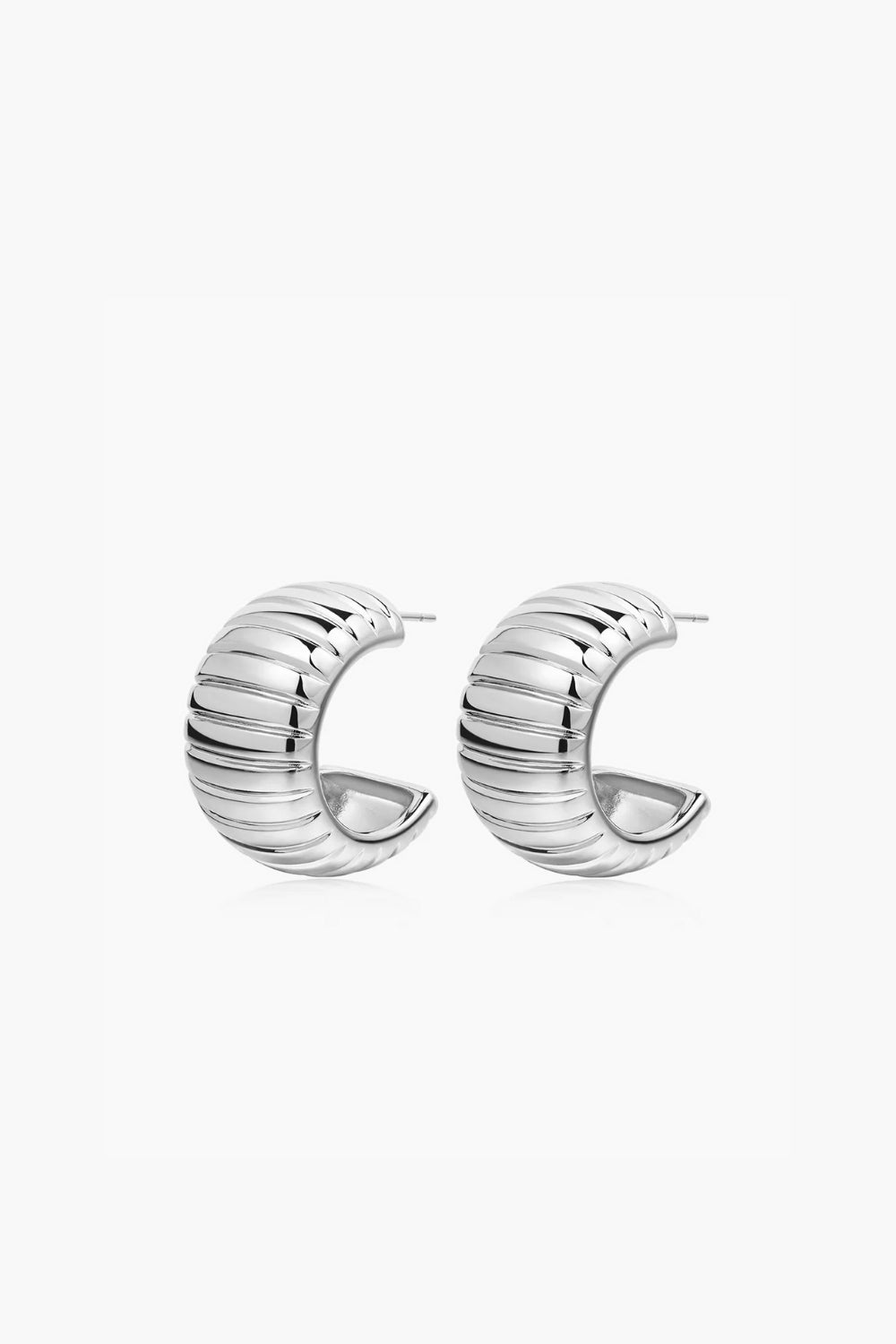 White gold huggie hoop earrings, ribbed on a white background.
