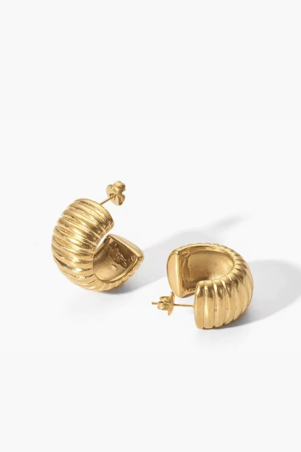 Yellow gold ribbed hoop earrings on a white background